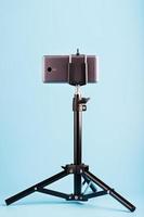 Smartphone on a tripod as a photo-video camera on a blue background. Record videos and photos for your blog.