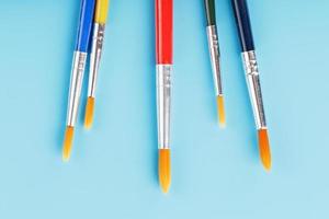 Brushes of different colors for drawing, creativity and art on a blue background. photo