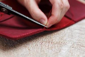 A leather craftsman works with leather. Sews leather goods. Making things handmade. photo