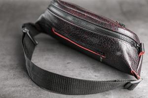 Bag on the belt of textured leather in Bordeaux colour , banana on a gray background. photo