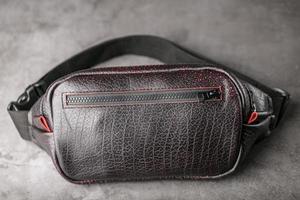 Bag on the belt of textured leather in Bordeaux colour , banana on a gray background. photo