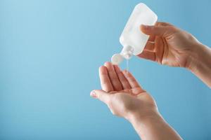 A bottle of Disinfectant gel in your hands on a blue background. Antiseptic treatment of hands from bacteria Sanitizer. photo