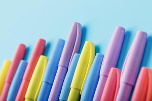Multi-colored pens on a blue background with free space. photo