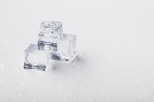cubos de hielo en forma de pirámide con gotas de agua cerca - en macro sobre un fondo blanco. foto