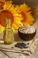 Sunflower oil in a bottle with sunflower seeds and flowers on a wooden background. photo
