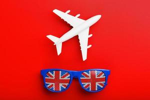 A white passenger plane flies in Sunglasses with the flag of the United Kingdom, on a red background. photo