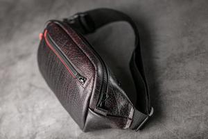 bolso en el cinturón de cuero texturizado en color burdeos, plátano sobre fondo gris. foto