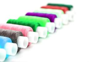 coloridos hilos de coser artesanales de algodón multicolores en una fila aislados en un fondo blanco. foto
