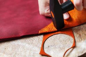 un artesano del cuero produce artículos de cuero. golpea el martillo. foto