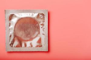 Condom transparent on a pink background, close-up, top view. Safe sex concept. photo