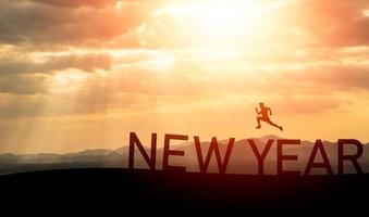 Sport man run jump happy new year 2023 concept, silhouette of man jumping over barrier cliff and success with beautiful sunset background. Happy New Year 2023 use for web banner and advertisement. photo