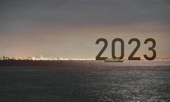 Happy new year 2023 boat on sea city night light success concept,  island sea cityscape at night lighting view success with sunset background. Happy New Year 2023 use for web banner and advertisement. photo