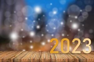 Happy new year 2023,2023 symbolizes the start of the new year. The letter start new year 2023 on the wooden table terrace night light bokeh background environment ecology greenery wallpaper concept. photo