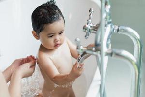 Asian cute kid girl toddler having a bath wash hair cleaning bathing bath tub with her mother. Mother love and care happy baby girl  innocent have fun playing with water enjoying. Baby concept. photo