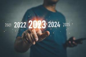 concepto de año nuevo 2023. Comience el feliz año nuevo 2023. Inversionistas de negocios que usan y la pantalla táctil del dedo del teléfono móvil diagrama virtual del año 2023, planificación comercial, estrategia, tendencias comerciales, inversión. foto