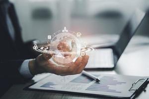 Man hand holding global earth Internet connection icon virtual screen working on laptop. Business global internet connection application technology and digital marketing financial and banking. photo
