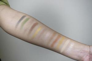 Image of a female arm displaying a wide range of colorful eyeshadow bands photo