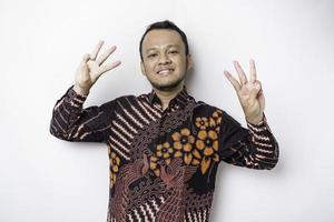 Excited Indonesian man wearing a batik shirt giving number 12345 by hand gesture photo