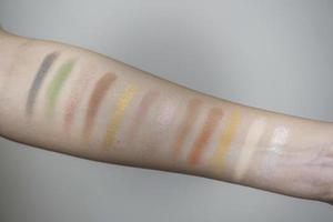 Image of a female arm displaying a wide range of colorful eyeshadow bands photo