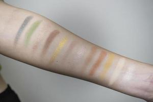 Image of a female arm displaying a wide range of colorful eyeshadow bands photo