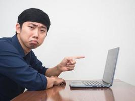 Male employee feels bored point finger at his laptop on the desk photo