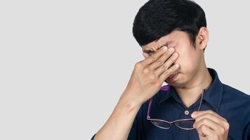 Close up young businessman tried from working gesture take off glasses isolated photo