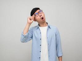 Young man wear glasses gesture shocked looking up isolated photo