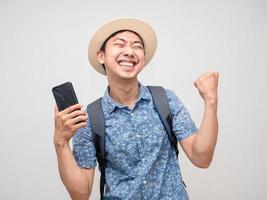 Asian man traveler hold mobile phone feels satisfied happy about booking holiday success isolated photo