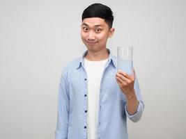 Positive asian man blue shirt show glass of water gentle smile isolated photo