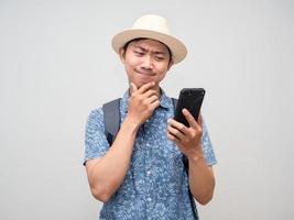 Traveler man hold mobile phone thoughtful about booking at holiday isolated photo