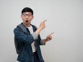 Cheeful hombre asiático jeans camisa usar gafas se siente sorprendido gesto señalar con el dedo aislado foto