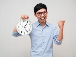 hombre de negocios asiático feliz sonrisa sosteniendo un reloj analógico muestra el puño para el éxito aislado foto