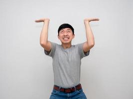 Young asian man grey shirt gesture carry something above himself feels heavy isolated photo