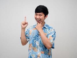 Tourism asian man beach shirt thinking about vacation and point finger up isolated photo
