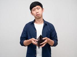 un pobre asiático muestra dinero vacío en su billetera y se siente triste y aislado foto