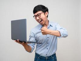 joven empresario enojado emoción gesto golpeado en la computadora portátil en la mano aislado foto