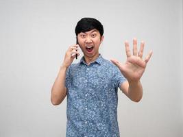 Asian man blue shirt talking with cellphone feels angry show hand stop isolated photo
