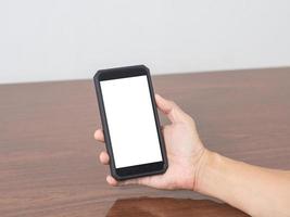 Close up man hold mobile phone blank white screen mockup on the table photo