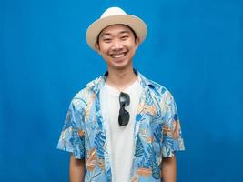 viajero hombre asiático use sombrero con gafas de sol feliz sonrisa fondo azul foto