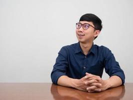 Positive asian businessman wearing glasses sit at desk gesture looking photo