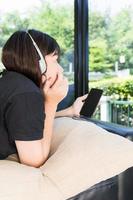 Young girl listening to music from mobile phone in living room photo