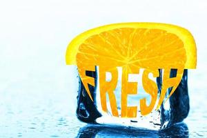 Fresh, creative text on an orange slice lying on an ice cube. photo