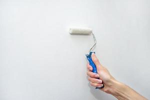 woman's hand painting the wall with a roller. Place for your text. Repair photo