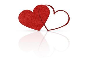 two glittering red hearts on a white glossy background. Valentine's Day photo