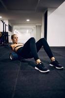 Motivated physically disabled sportswoman using foam roller while exercising in a gym. photo