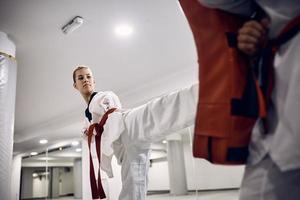 luchadora de taekwondo con paracapacidad practicando su patada con el entrenador en el club de salud. foto
