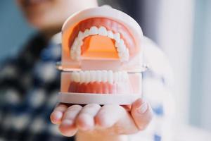 Stomatology concept, partial portrait of girl with strong white teeth looking at camera and smiling, fingers near face. Closeup of young woman at dentist's, studio, indoors photo