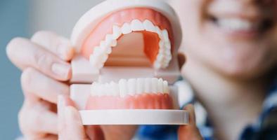 Stomatology concept, partial portrait of girl with strong white teeth looking at camera and smiling, fingers near face. Closeup of young woman at dentist's, studio, indoors photo