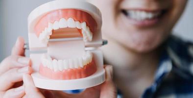 Stomatology concept, partial portrait of girl with strong white teeth looking at camera and smiling, fingers near face. Closeup of young woman at dentist's, studio, indoors photo