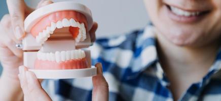 Stomatology concept, partial portrait of girl with strong white teeth looking at camera and smiling, fingers near face. Closeup of young woman at dentist's, studio, indoors photo